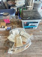 Lot overview showing wall plates, roofing nails pail, jars and bag of screws