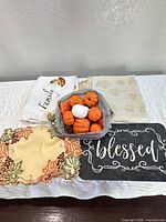 Group shot showing both tablecloths, embroidered placemats, plastic placemat and bag of stuffed pumpkins