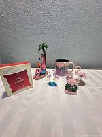 Group shot of all flamingo items: boxed ornament, resin figurine, mug, glass figurines, salt & pepper shakers