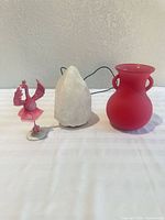 Flamingo figurine, salt lamp, red vase grouped on table