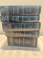 Spine view of all five black leatherette books showing titles and gilt decoration