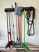 Overall view of long-handled tools on wall rack