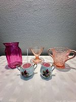 Group shot showing all five items: pressed-glass vase, depression-glass compote, pressed-glass sugar pitcher, porcelain creamer and sugar bowl