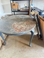 Full view of oval dining table top showing distressed finish and wear