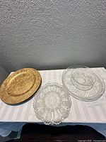 Stacked gold charger plates, clear chip-and-dip set with bowl, clear deviled-egg platter on table