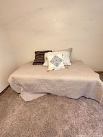 Overall view of twin bed with quilt and pillows