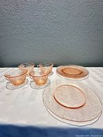 Four pink glass tea cups and four matching dessert plates displayed on table