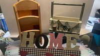 All three wooden décor items grouped: HOME sign front, wall shelf left, rustic caddy right