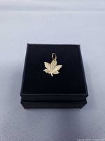 Front view of gold maple leaf charm on display pad