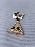 Front view of triangular gold tone watch fob