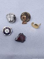 Front view showing all five pins: baby feet, number 2 disc, numeral 6, Gregg College hexagon, WHHS shield