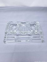 Top view of clear glass double inkwell stand showing two round recesses, central slot and stepped base