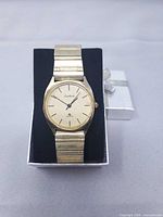 Front view of Cardinal gold-tone watch on display box