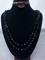 Full view of the two-strand black faceted glass bead necklace on display bust