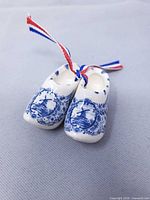 Full view of pair of Delft ceramic clogs with ribbon