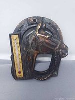 Front view of copper-tone cast metal horseshoe with horse head relief and integrated thermometer