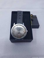 Full watch in box showing case, dial and partial strap