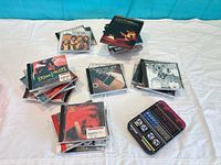 Multiple stacks of CDs with Stone Temple Pilots and Beatles albums visible plus metal tin