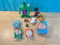 Loose Hulk, other figures, sealed Tarzan and Ty Happy Meal toys on tabletop