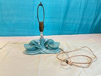 Front view of blue ceramic lamp with twin dancers, metal socket and harp visible, cord extended