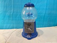 Full view of blue gumball machine showing glass globe, base, and lid