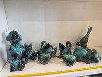 Full group of nine Blue Mountain Pottery animal pieces on shelf