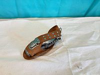 Multitool folded inside brown leather sheath with rivets and snap