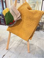 Yellow quilt and striped crochet afghan draped on easel