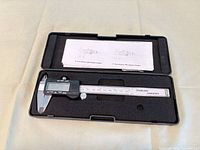 Caliper in case showing LCD side, foam insert, instruction sheet