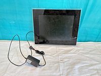 Front view of digital photo frame with attached power adapter