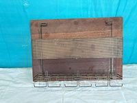 Front view showing wood panel, metal mesh pocket and five hooks