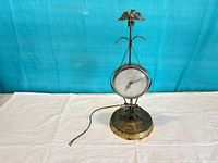 Front view of brass-tone electric clock showing face and eagle finial