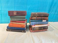 Two stacks of vintage cloth-bound hard-cover books showing colours and relative quantity