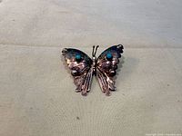 Front view of sterling silver butterfly brooch with turquoise cabochons