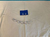 Full view of necklace and earrings set laid flat