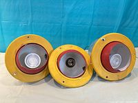 Front view of three yellow-trim pot lights showing reflector and inner ring