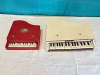 Top and front view of both toy pianos showing keys, lids and overall condition