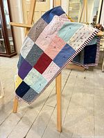Front view of multicolour patchwork quilt draped over easel