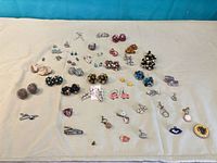 Full layout of assorted earrings and brooches on cloth