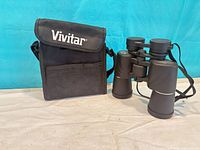 Binoculars standing next to branded carrying case