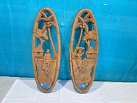 Front view of both carved wood plaques showing relief scenes