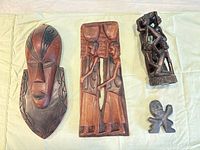 Front view of wooden mask, plaque, totem carving and stone figure
