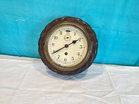 Front view of wooden wall clock showing dial and bezel