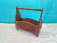 Front view of carved wooden magazine stand showing floral fretwork and handle