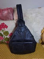 Front view of black leather triangular backpack purse with front pocket
