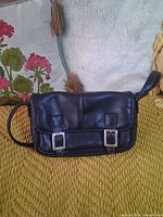 Front view of black leather crossbody purse showing flap and buckle accents