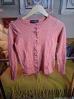 Front view of peach button-up cardigan on hanger