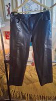 Full front view of chocolate brown leather pants on hanger