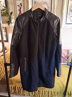 Full front view of black Danier leather and wool long jacket on hanger