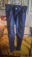 Front view of Hudson Ethan jeans hanging, showing full length and knee panel details
